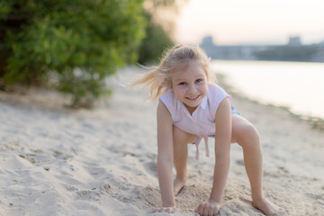  Smiling blonde child on summer. adorable kids, childhood, emotions concept.Summer portrait smiling child little girl lying on sand beach