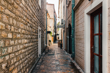 Fototapeta premium Narrow street with old historical buildings in the central district of ancient city Budva, Montenegro