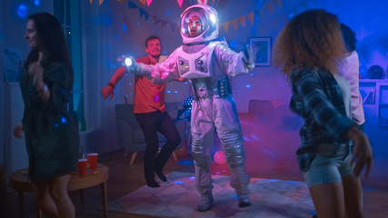 At the College House Costume Party: Fun Guy Wearing Space Suit Dances Off, Doing Robot Dance Modern Moves. With Him Beautiful Girls and Boys Dancing in Neon Lights.