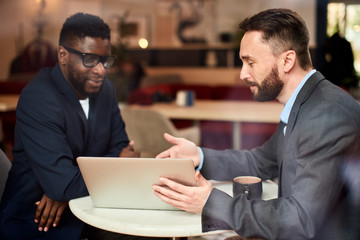 Two businessmen having a discussion on what they see on a laptop screen.