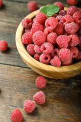 Fresh raspberries in a wooden bowl on a wooden table