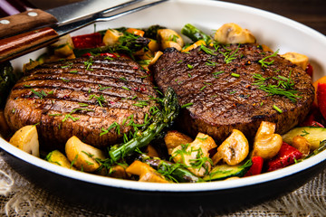 Grilled steak, baked potatoes and vegetables