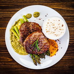 Grilled steak with asparagus on wooden background