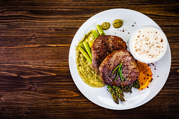 Grilled steak with asparagus on wooden background