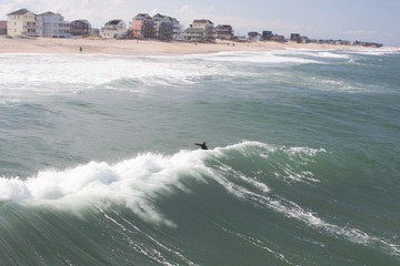 Surfing along pier with waves breaking