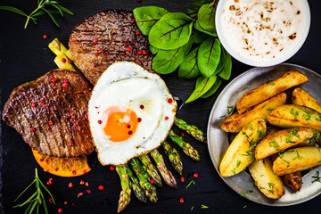 Grilled steak with asparagus, fried egg and french fries