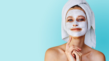 Beautiful young woman with facial mask on her face. Skin care and treatment, spa, natural beauty...