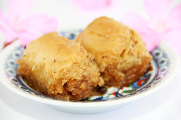 traditional Turkish sweetness baklava on plate with patterns and decor of pink flowers
