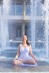 young woman doing yoga pose in city fountain