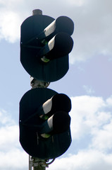 Street railway traffic light with four lamps against the blue sky.