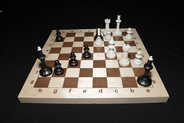 Wooden chessboard and black pieces for skill background