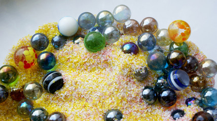 bright background beautiful colorful glass balls in yellow with pink and white sand