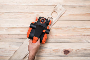 Electric planer in the male hand. Processing of the workpiece on a light brown wooden table. Directly above, copy space