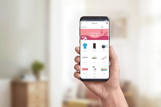 Hand showing online store app on a modern smart phone. Concept of online shopping and grab deals, discount marketing. Product categories and shopping cart.