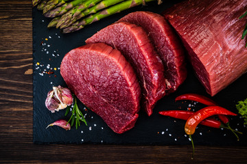 Fresh raw beef steaks with asparagus on wooden background