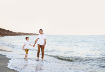 Fototapeta na wymiar Father and son go by the hand along the sea coast. Family vacation. Friendship