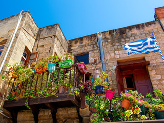 Fototapeta na wymiar Residential house with balcony in Rhodes (Greece) with colorful flowerpots