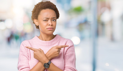 Beautiful young african american woman over isolated background Pointing to both sides with fingers, different direction disagree