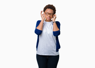 Young beautiful african american woman wearing glasses over isolated background covering ears with fingers with annoyed expression for the noise of loud music. Deaf concept.