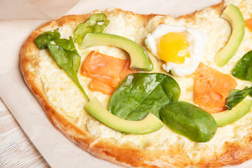 Salmon pie, egg and avocado on wooden background.