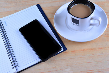 Blank Notebook, fountain pen, smartphone and cup of coffee on work desk
