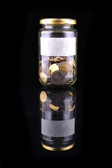 Glass jar with coins isolated on black background