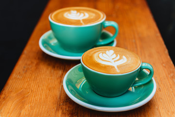 Two cups of cappuccino on wooden background.