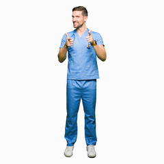 Handsome doctor man wearing medical uniform over isolated background pointing fingers to camera with happy and funny face. Good energy and vibes.