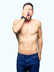 Fototapeta premium Handsome shirtless man showing nude chest Yawning tired covering half face, eye and mouth with hand. Face hurts in pain.