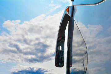 Rearview mirror in the bus. The sky in the background.