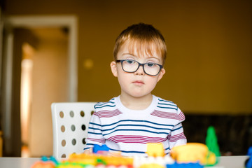Naklejka na ściany i meble little ginger boy with glasses with syndrome dawn playing