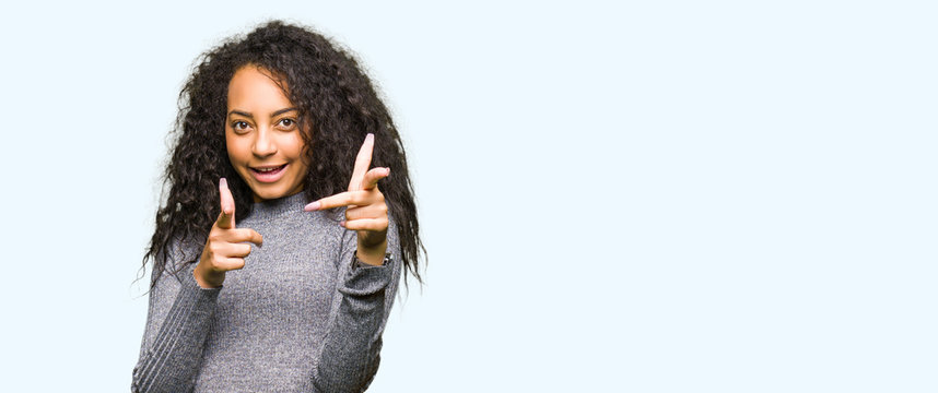 Young beautiful girl with curly hair pointing fingers to camera with happy and funny face. Good energy and vibes.