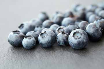 bunch of blueberry berries close-up on a dark stone background, strong blur background