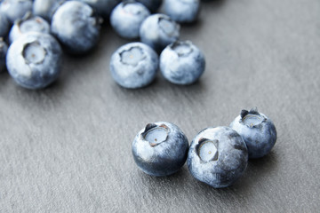 bunch of blueberry berries close-up on a dark stone background, strong blur background