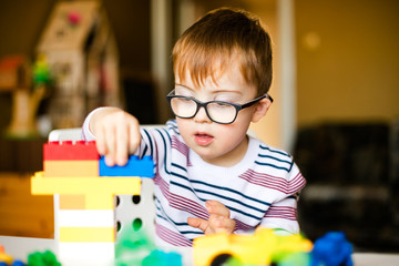 little ginger boy with glasses with syndrome dawn playing