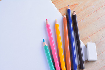 Blank paper and colorful pencils on the wooden table. View from above