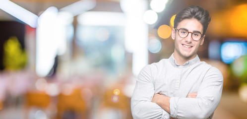Fototapeta na wymiar Young handsome man wearing glasses over isolated background happy face smiling with crossed arms looking at the camera. Positive person.