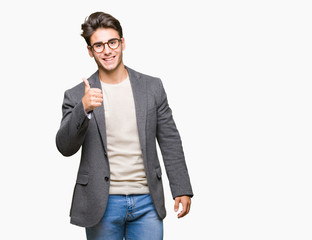 Young business man wearing glasses over isolated background doing happy thumbs up gesture with hand. Approving expression looking at the camera showing success.