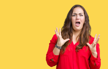 Beautiful plus size young business woman over isolated background crazy and mad shouting and yelling with aggressive expression and arms raised. Frustration concept.