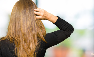 Fototapeta premium Beautiful middle age woman wearing rock and roll sweater Backwards thinking about doubt with hand on head