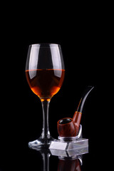 Wine glass and smoking pipe on black background