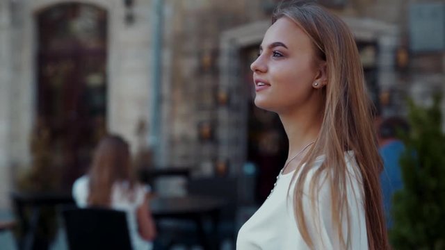 Confident young stylish fancy woman walking down the city, excitedly looking around with charming smile on her face. Dreamy mood, romantic atmosphere, positive emotions. Female portrait