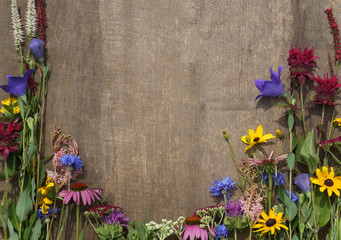 Horizontal image of a collection of colorful summer flowers against a weathered wood background,...