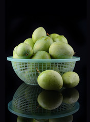 Fresh green mango in basket over black background
