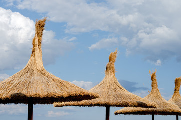 Reed umbrella roof against blue cloudy  sky  on  summer time   at beach .