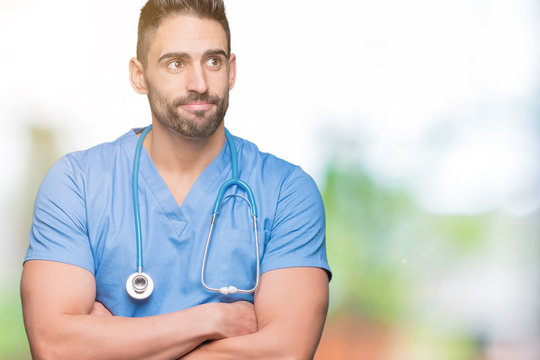 Handsome young doctor surgeon man over isolated background smiling looking side and staring away thinking.