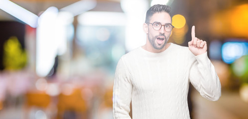 Young handsome man wearing glasses over isolated background pointing finger up with successful idea. Exited and happy. Number one.