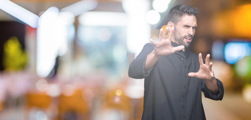 Young Christian priest over isolated background afraid and terrified with fear expression stop...