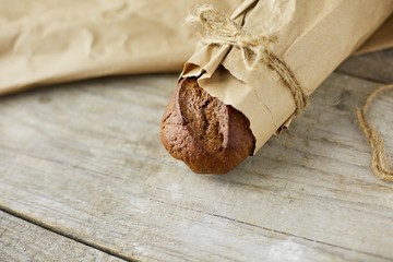 Fresh baked bread wrapped in paper, on wooden background