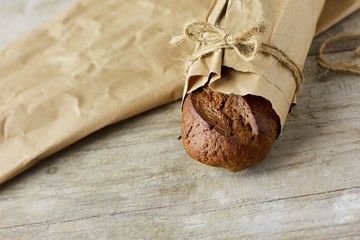 Fresh baked bread wrapped in paper, on wooden background